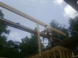 Carpenter setting a ridge beam over a new addition frame — Ice Dam Removal by Roofing Brothers in Amityville