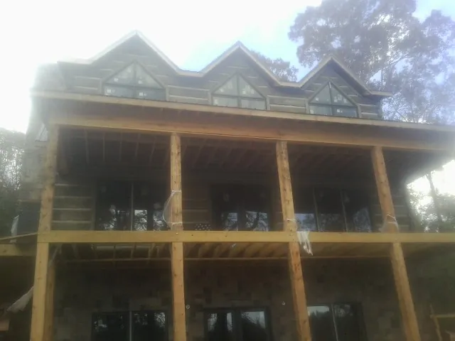 Dormers and porch framing on a large log home under construction — Roof Coating work by our crew in Amityville
