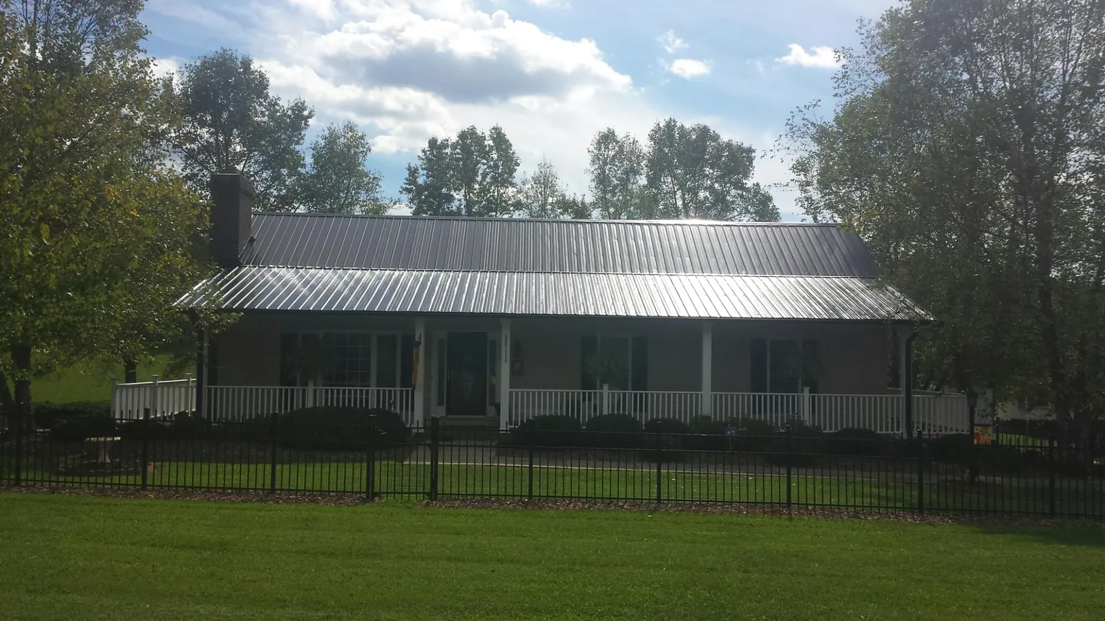 Gray metal roof on a brick ranch with a full width front porch — Gutter Guard Installation work by our crew in Amityville