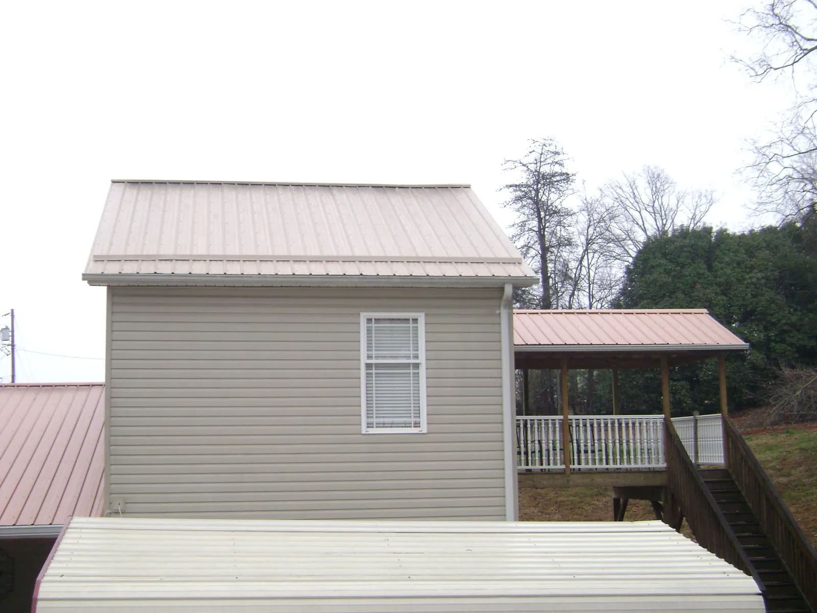 Tan metal roofs on a two story addition and attached porch, from a Roof Replacement job in Amityville