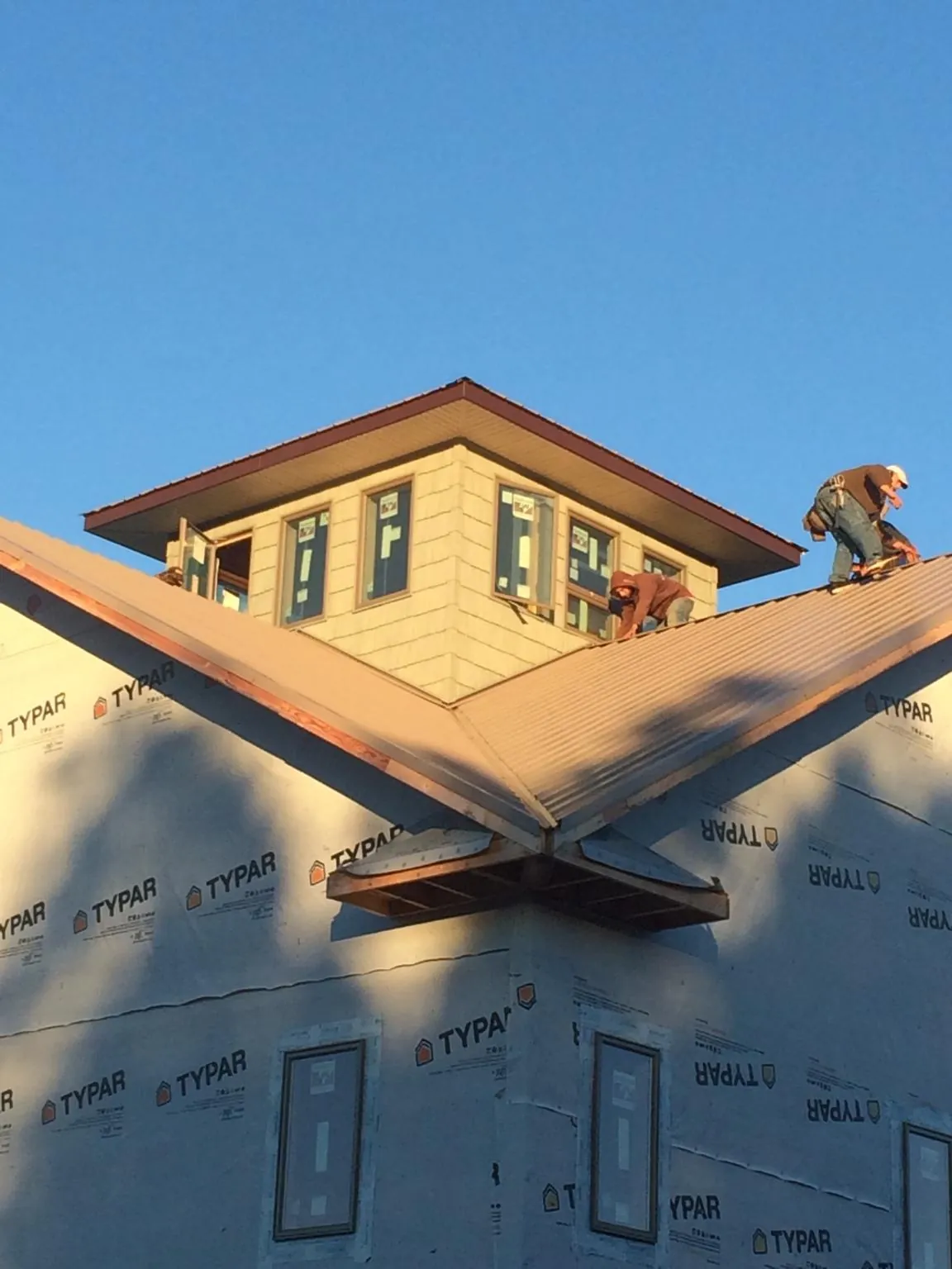 Roofers working around a rooftop cupola on a new metal roof at sunset — Roof Waterproofing in Amityville by Roofing Brothers